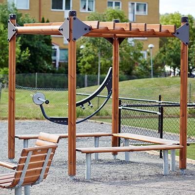 Eine Pergola inmitten eines Parks, mit Freizeiteinrichtungen drum herum.